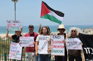 Israeli activists holding placards and waving a Palestinian flag gather in protest near the port of Ashdod, Israel
